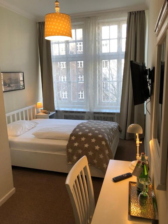 汉堡达姆托帕拉斯菲森纳酒店的一间卧室设有一张床、一个窗口和一张桌子