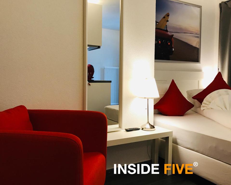 苏黎世INSIDE Five的一间设有红色椅子和一张带镜子的床的房间