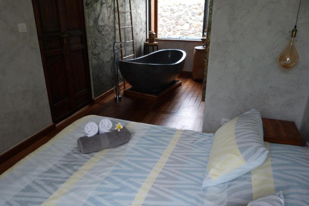 Le GuillaumeL'Orée du Maïdo的一间带浴缸的卧室和一张带两条毛巾的床