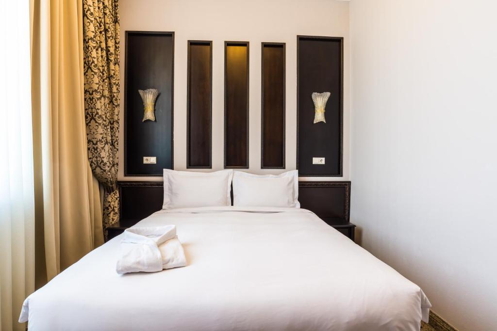塔尔迪库尔干Royal Petrol Hotel的一间卧室配有一张带白色床单的大床
