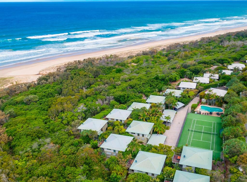 佩里吉安比奇海滨别墅度假酒店的享有海滩的空中景致,设有房屋和网球场