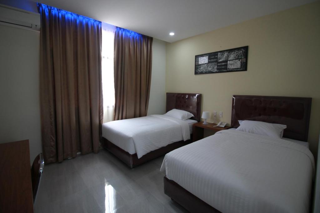 班达亚齐Grand Mahoni Hotel的酒店客房设有两张床和窗户。