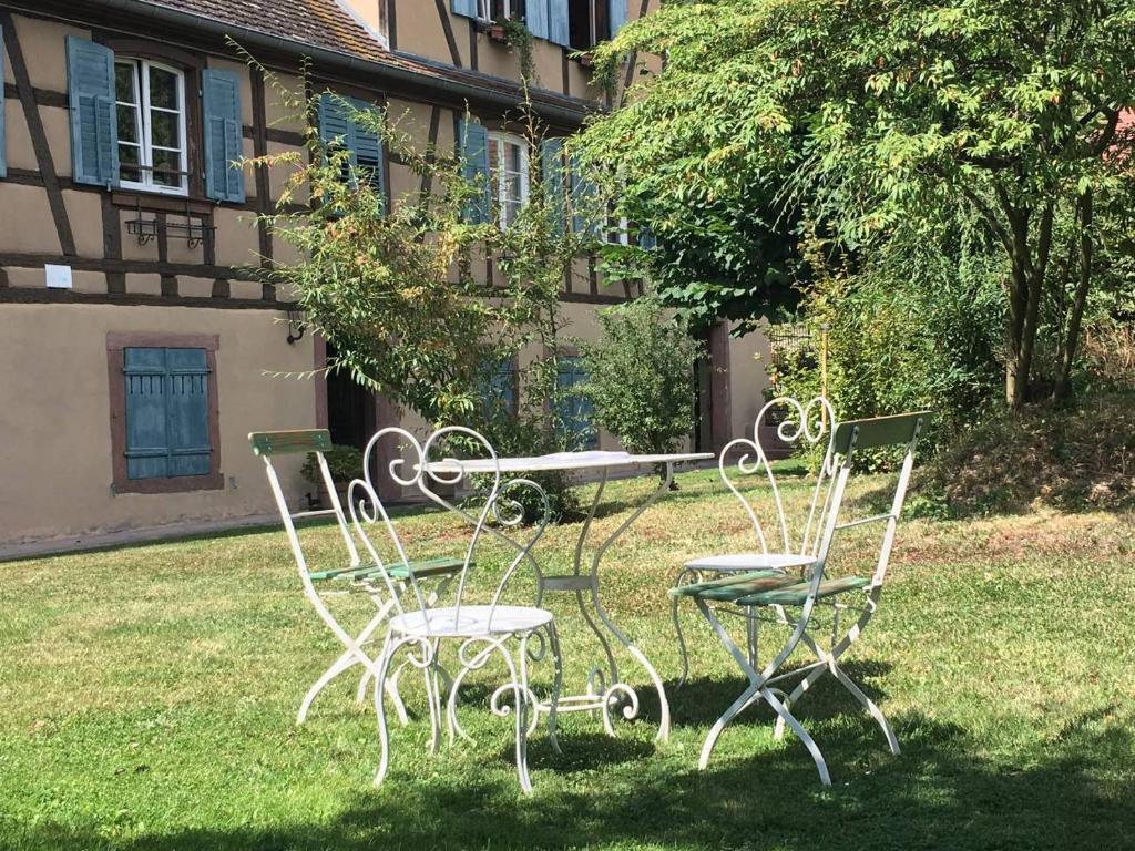 希伯维列Le Gîte du Moulin的草上一组椅子和一张桌子