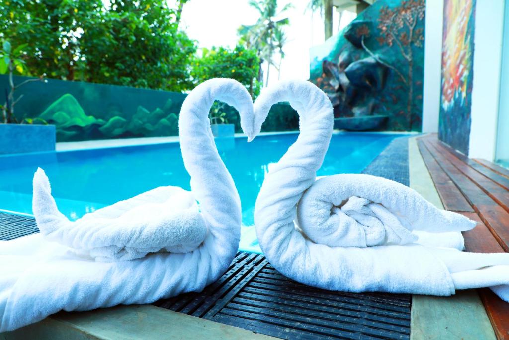 阿杭格默Hotel Sanmark的两个白天鹅坐在桌旁的游泳池边