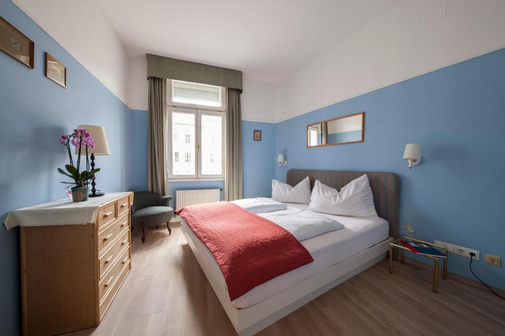维也纳蒙迪艾尔公寓酒店的一间拥有蓝色墙壁的卧室和一张带红色毯子的床