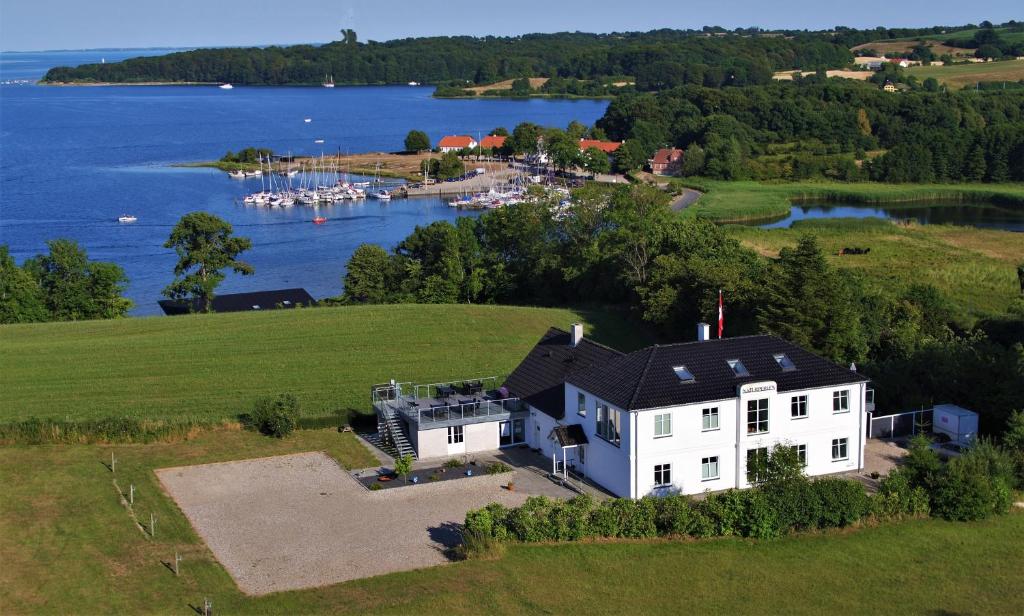RødekroNaturperlen的享有湖畔小山上白色房子的空中景色
