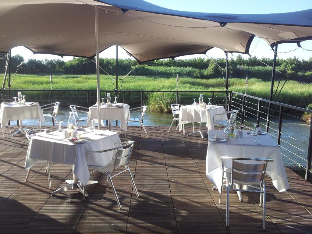 Kanoneiland奥兰耶鲁度假村的一个带白色桌子和椅子的甲板,在伞下
