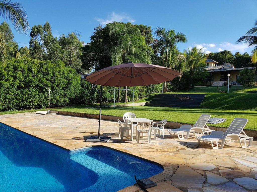 圣若昂-达巴拉Rancho Hollywood - Lago de Furnas的游泳池旁配有遮阳伞的桌椅