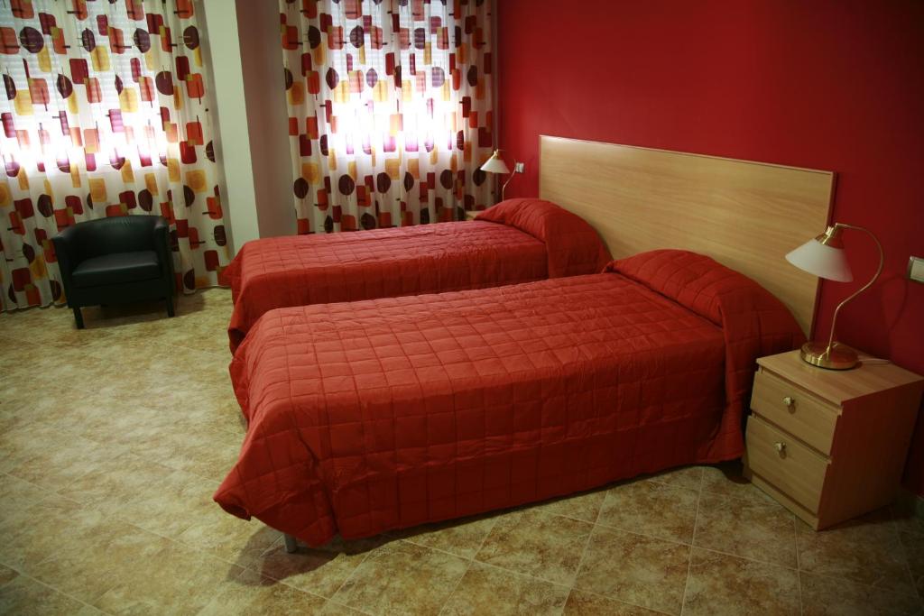 拉罗达HOSTAL EL POLIGONO的红色墙壁的酒店客房内的两张床