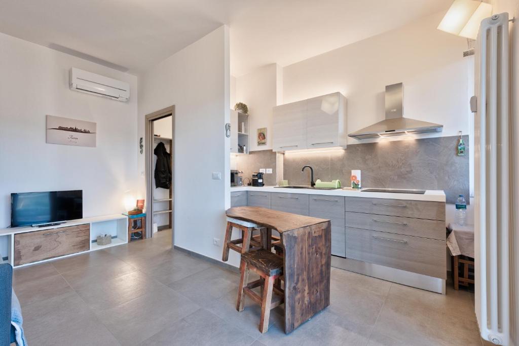 都灵Attico Valentino Cellini的厨房配有白色橱柜和木桌