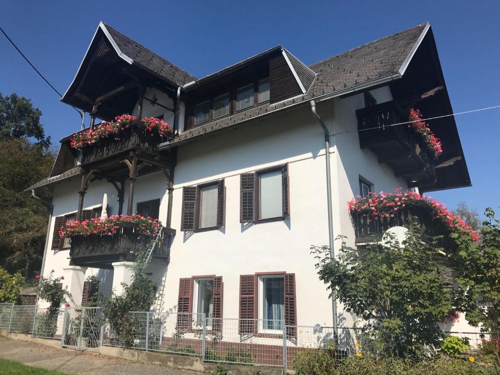 韦尔特湖畔克伦彭多夫Villa Nusswald的阳台上的白色房子,鲜花盛开