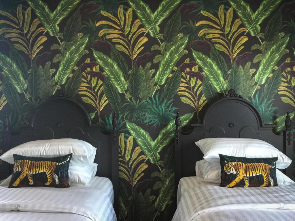 曼谷WIW mini hotel的一间卧室配有两张床和壁画