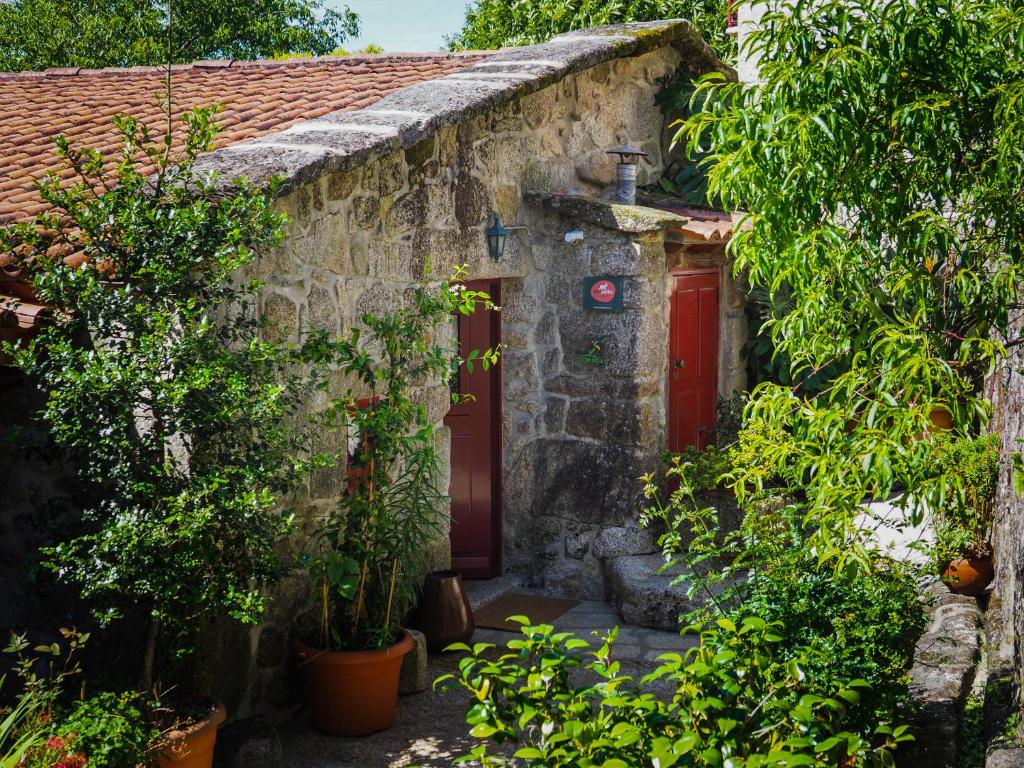 索茹Casa Das Videiras的一座石屋,有红色的门和一些植物