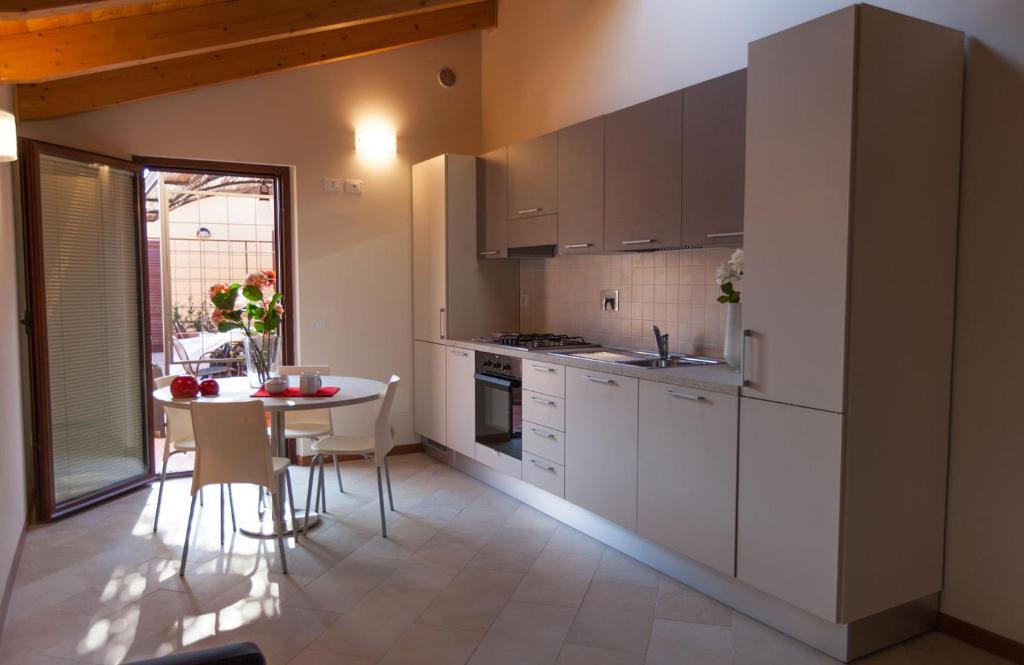 卡斯蒂里昂纳·德拉佩"La Terrazza di Castiglione" APPARTAMENTI VACANZA的厨房配有白色橱柜和桌椅