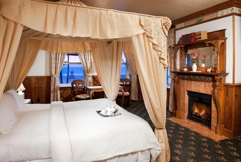 纽波特海滩Doryman's Oceanfront Inn的一间卧室设有一张天蓬床和一个壁炉