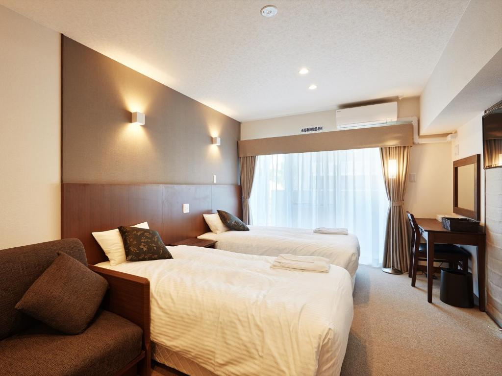 那霸Creass Hotel Tsubogawa Marche的酒店客房,设有两张床和一张沙发