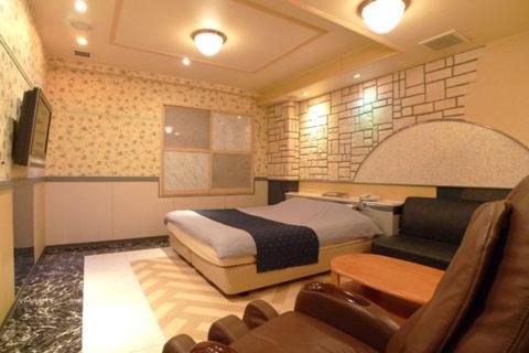 厚木Hotel GOLF II Atsugi (Adult Only)的一间卧室配有一张床、一张沙发和一把椅子