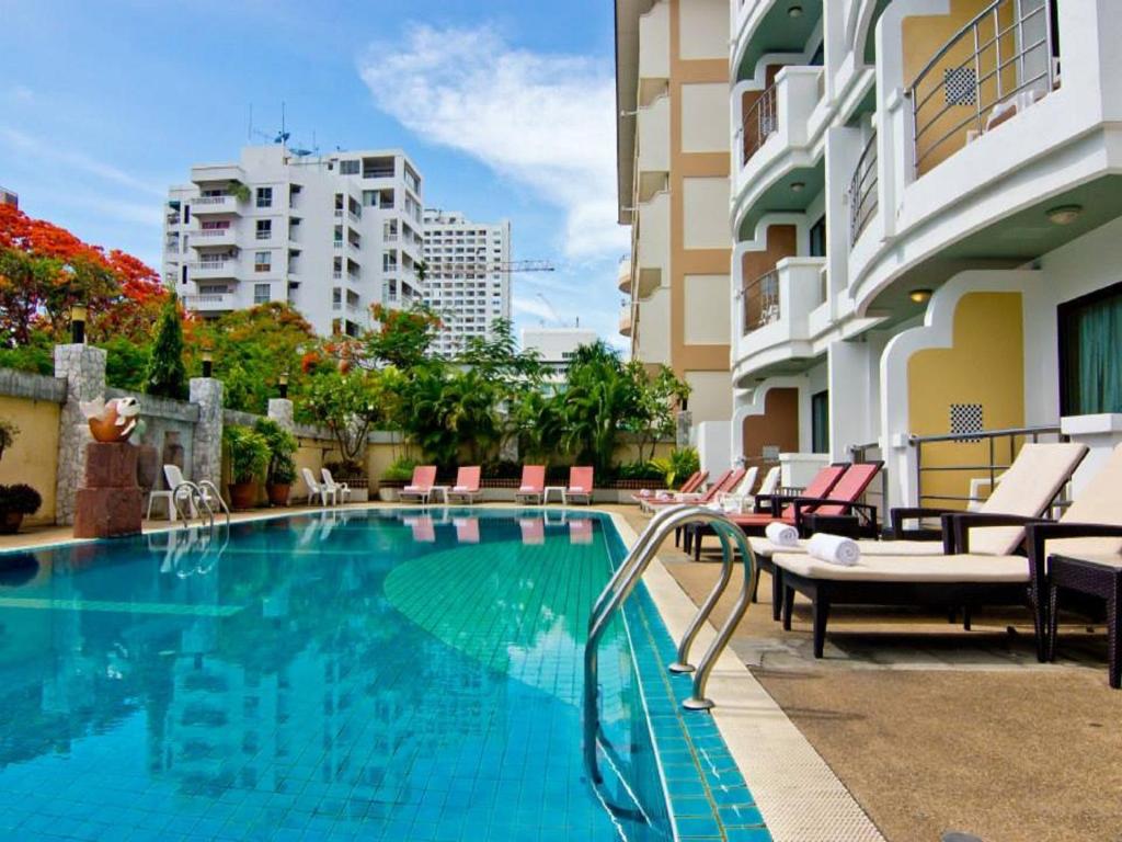 芭堤雅市中心最佳海滩别墅酒店的一座带椅子的游泳池以及一座建筑