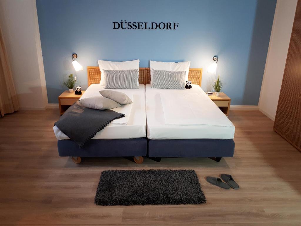 杜塞尔多夫KEMPE康福特酒店的卧室配有一张大床,地板上放着两双鞋