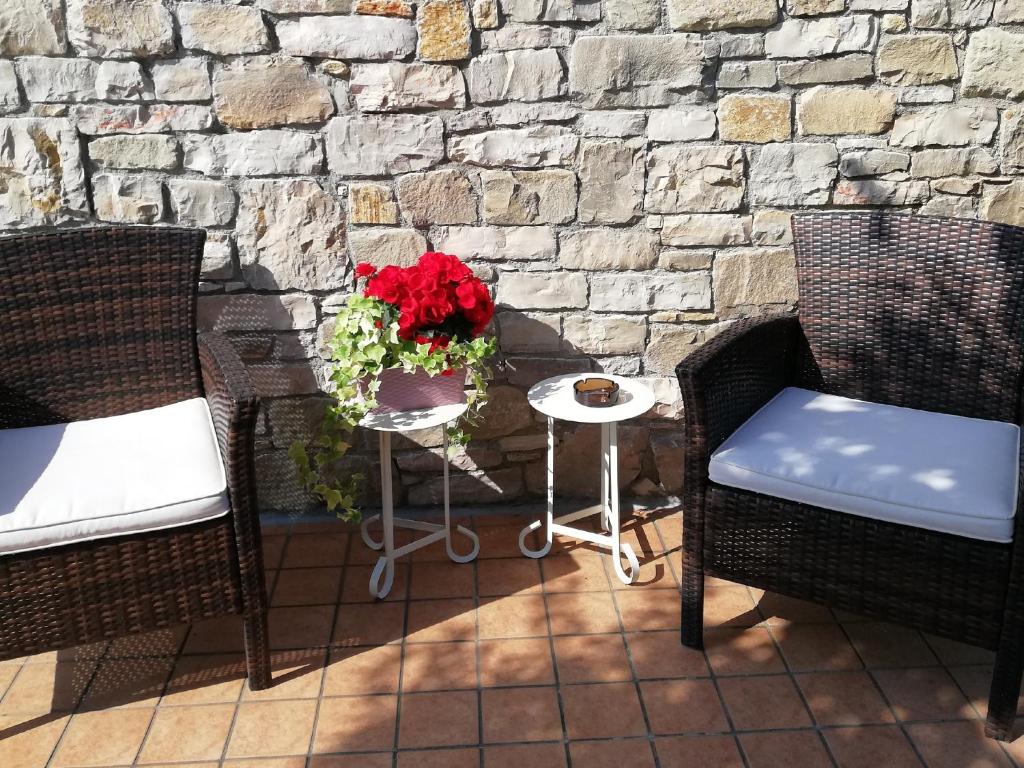埃尔布斯科ACERO ROSSO B&B in Franciacorta的庭院设有两把椅子和一张红花桌子