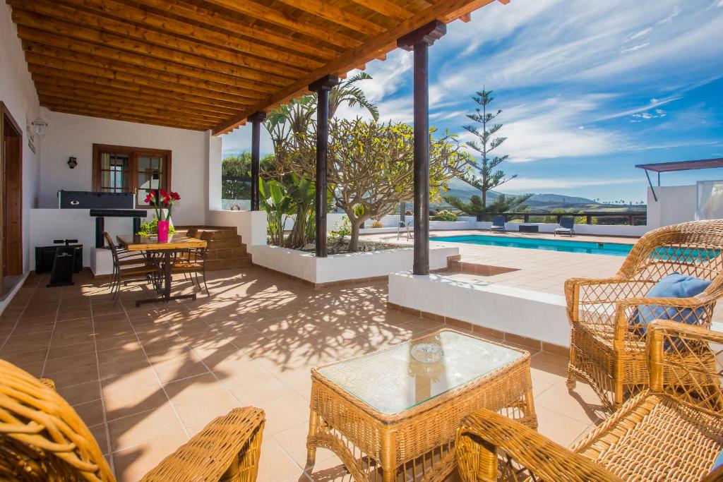 La VeguetaCasa El Quinto的一个带藤椅和桌子的庭院和一个游泳池