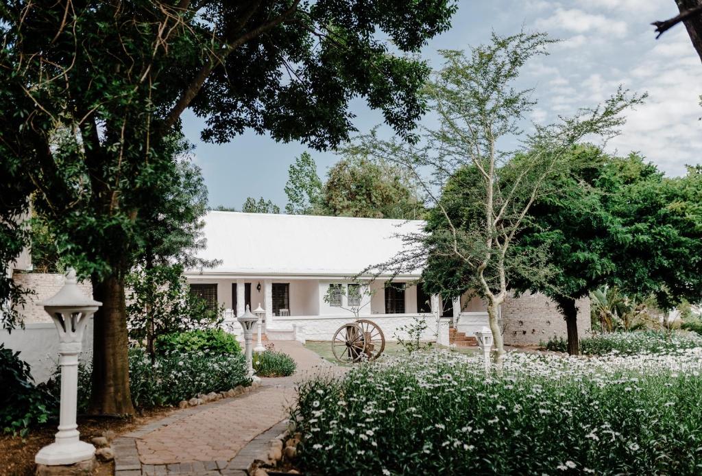 奥茨胡恩De Opstal Country Lodge的白色的房屋,有树木和白色的花