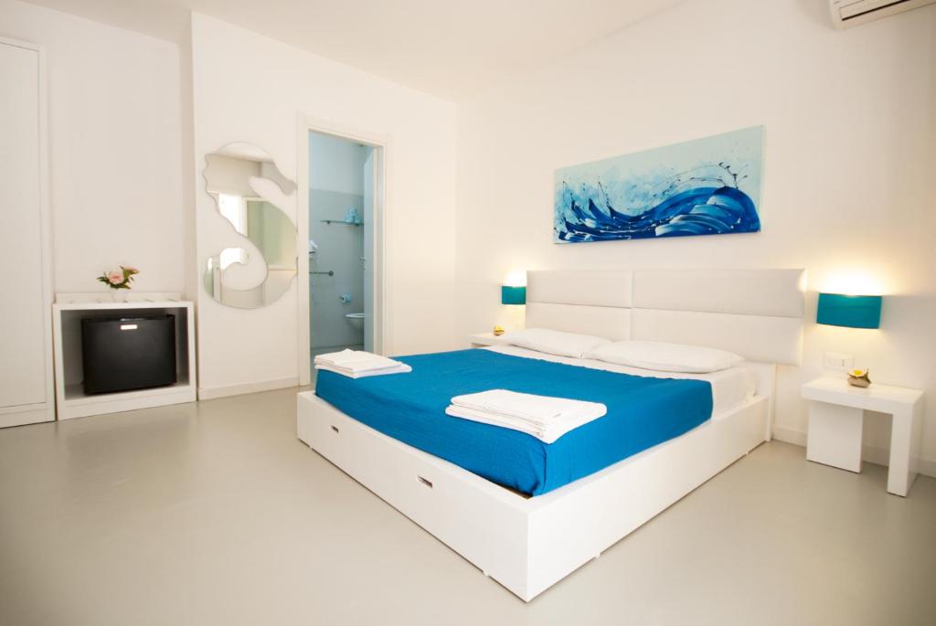 佩斯科勒海滨Hotel Beach Salento的白色卧室配有蓝色的床和电视
