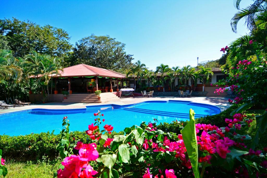 卡里略Hotel Hacienda del Mar的一座游泳池,位于一个拥有粉红色花卉的庭院内