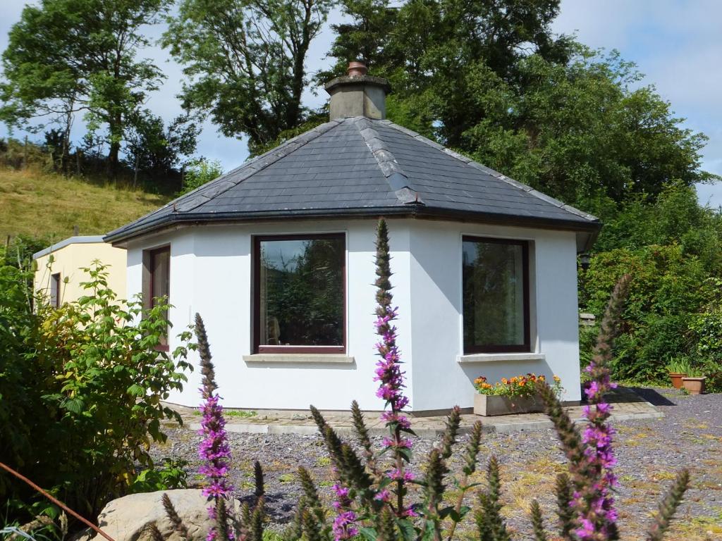 班特里Drombrow Cottage的一间黑色屋顶的白色小房子