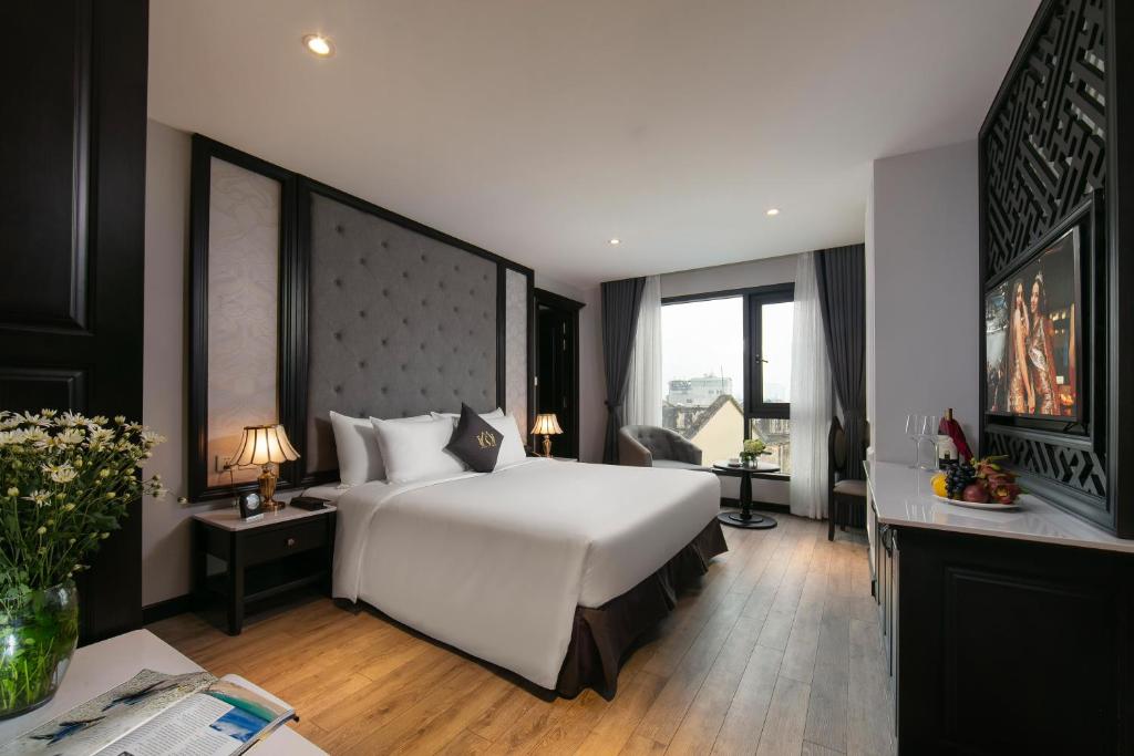河内Sen Grand Hotel & Spa managed by Sen Group的卧室配有一张白色大床和一张书桌
