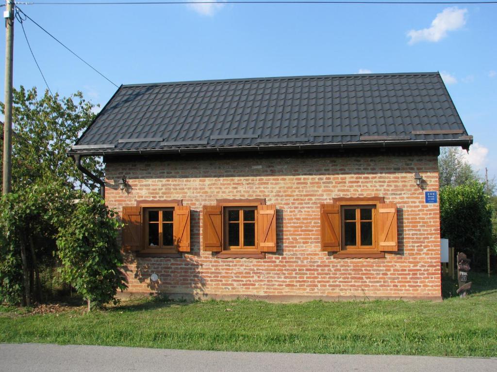PotokCottage Plavi Lav Potok的砖屋,设有棕色的窗户和黑色的屋顶