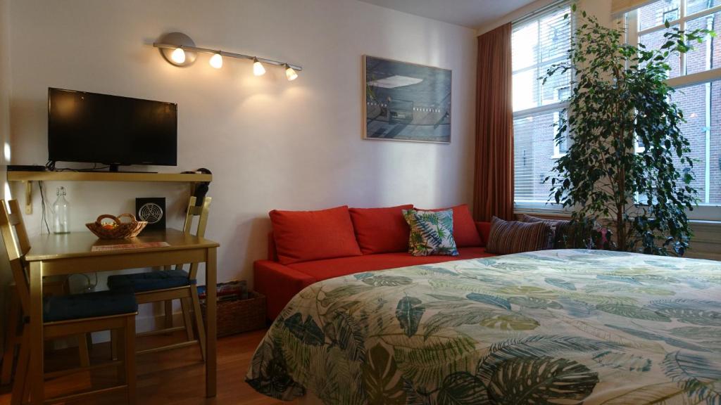 阿姆斯特丹Huis Roomolen的一间卧室配有一张床和一张红色的沙发