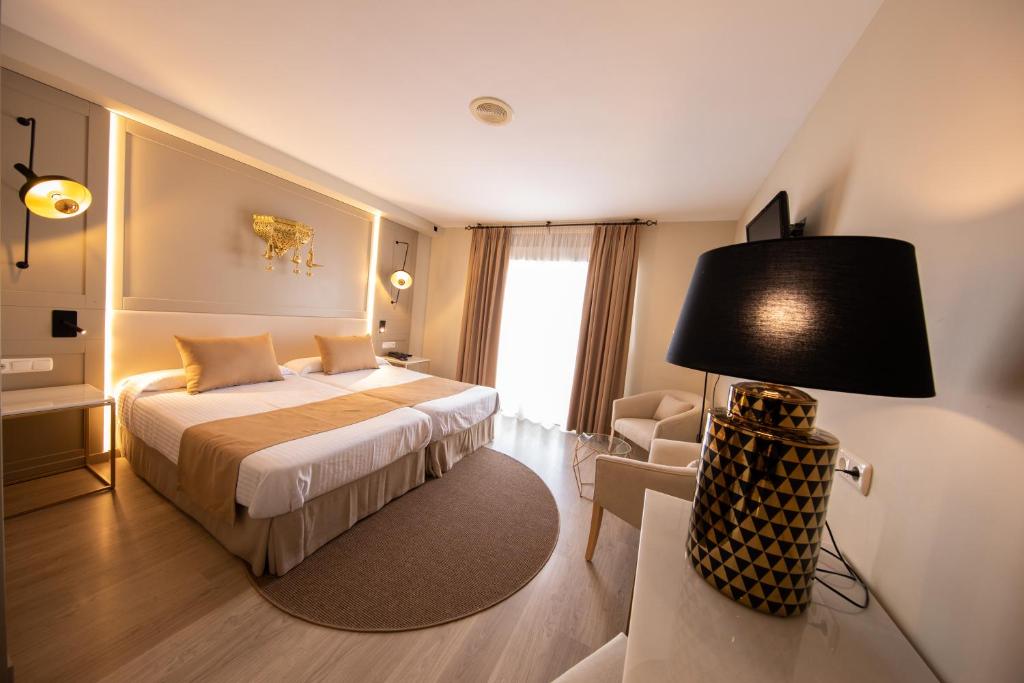 阿尔姆尼卡卡萨布兰卡酒店的一间卧室配有一张床、一盏灯和一把椅子