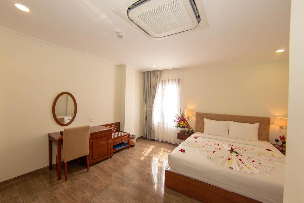芽庄Trường Hải Hotel的一间卧室配有一张床、一张书桌和一面镜子
