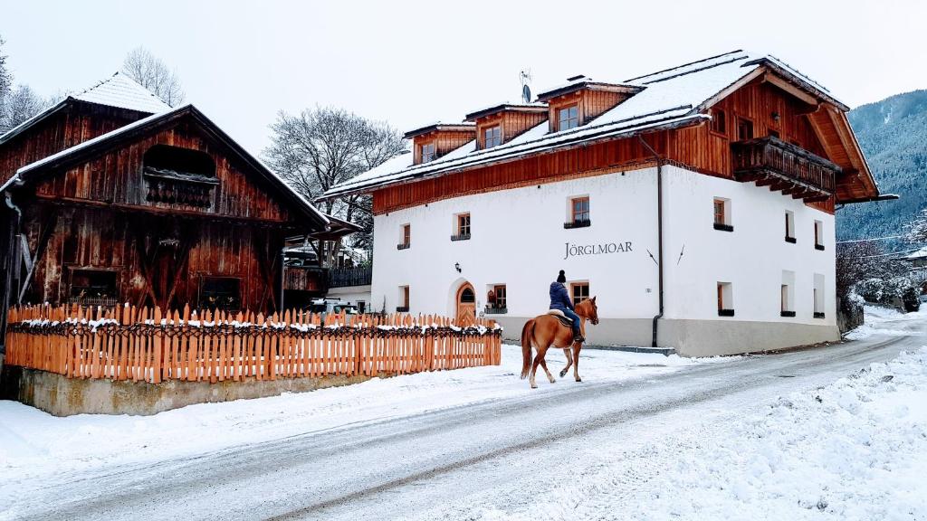 圣洛伦佐-迪塞巴托乔格尔莫农家乐的骑着马在建筑物旁边雪地里的人