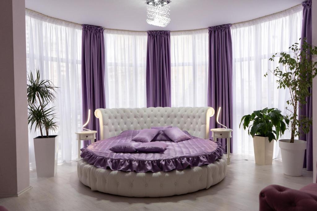 尼什罗特斯戈尔尼酒店的一间卧室配有一张带紫色枕头的大床