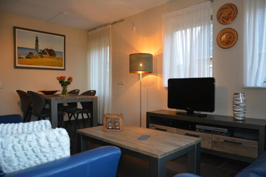 HollandscheveldAppartement Derde Zandwijkje的客厅配有电视和蓝色沙发。
