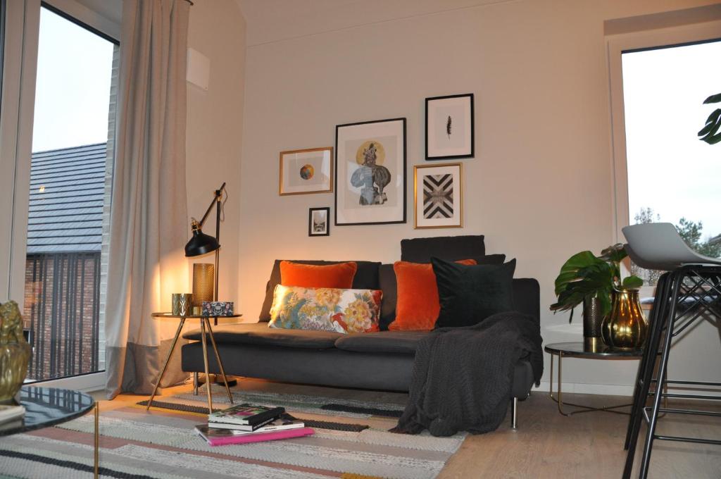 瑞林根Lieblingsplatz的客厅配有黑色沙发和橙色枕头。
