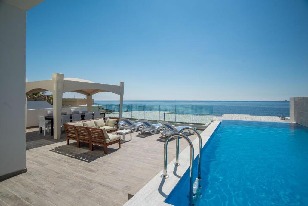 马尔萨斯卡拉The Sea-Bank Villa Apartments的一个带椅子的游泳池和一个毗邻大海的凉亭