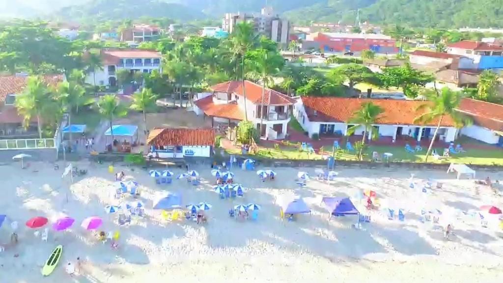 乌巴图巴Hotel Porto do Eixo Ubatuba的一群人在海滩上,带遮阳伞