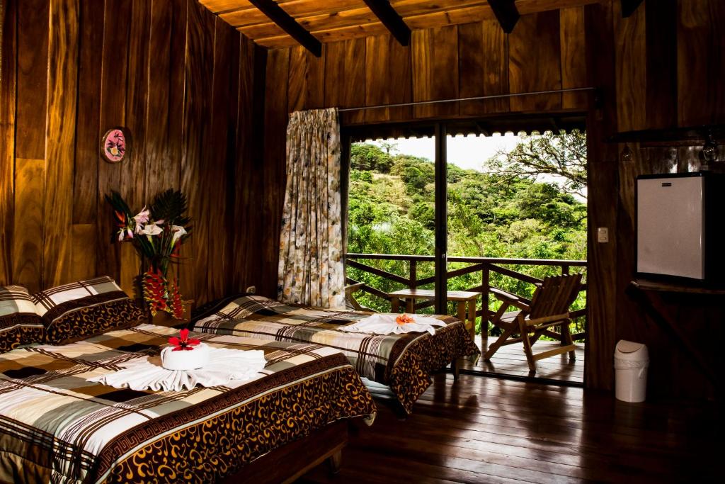 蒙泰韦尔德哥斯达黎加Cabinas Capulin & Farm的客房设有两张床和一个美景阳台。
