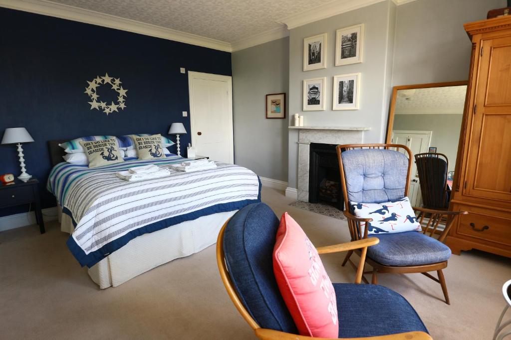 罗宾胡兹贝撒克逊别墅 的一间卧室配有一张床、两把椅子和一个壁炉