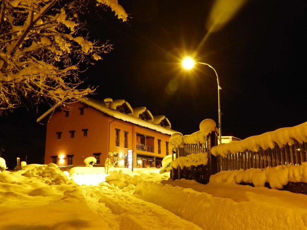 El PinoHotel Rural El Fundil的雪覆盖在晚上的房屋,有街灯