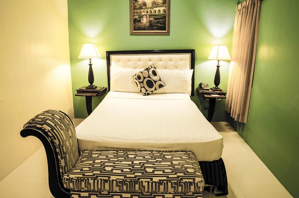 IlaganDreamwave Hotel Ilagan的一间卧室配有一张带椅子的床和两盏灯。