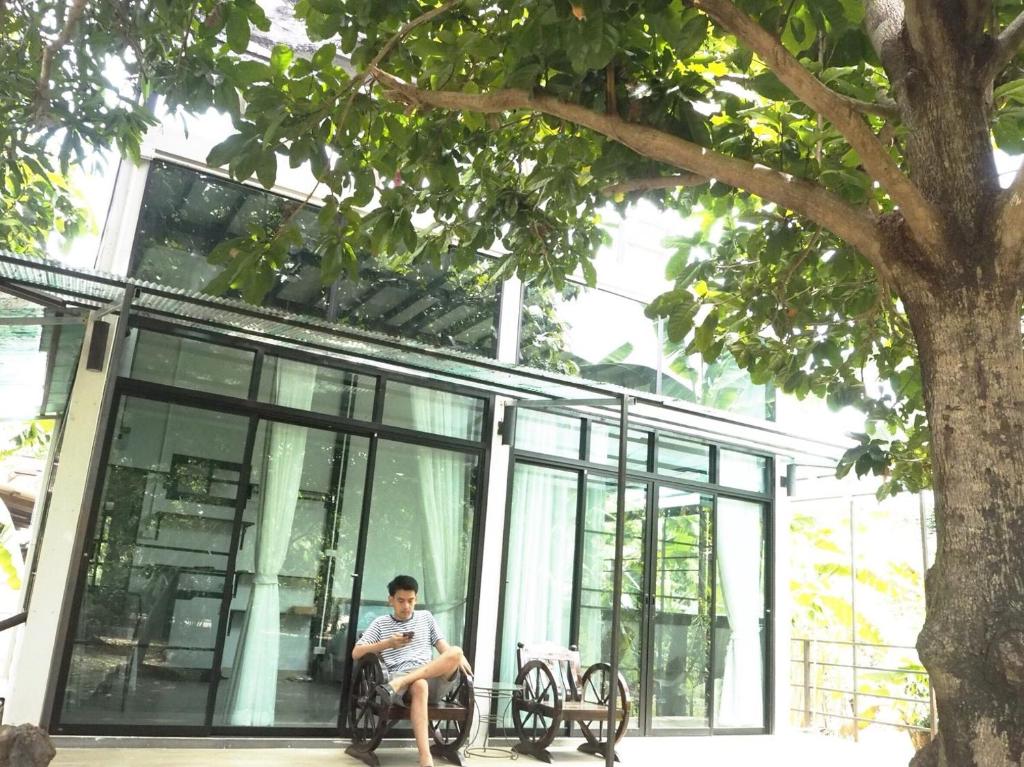 Ban Muang Chum班莱克莱昂民宿的坐在大楼前长凳上的男人