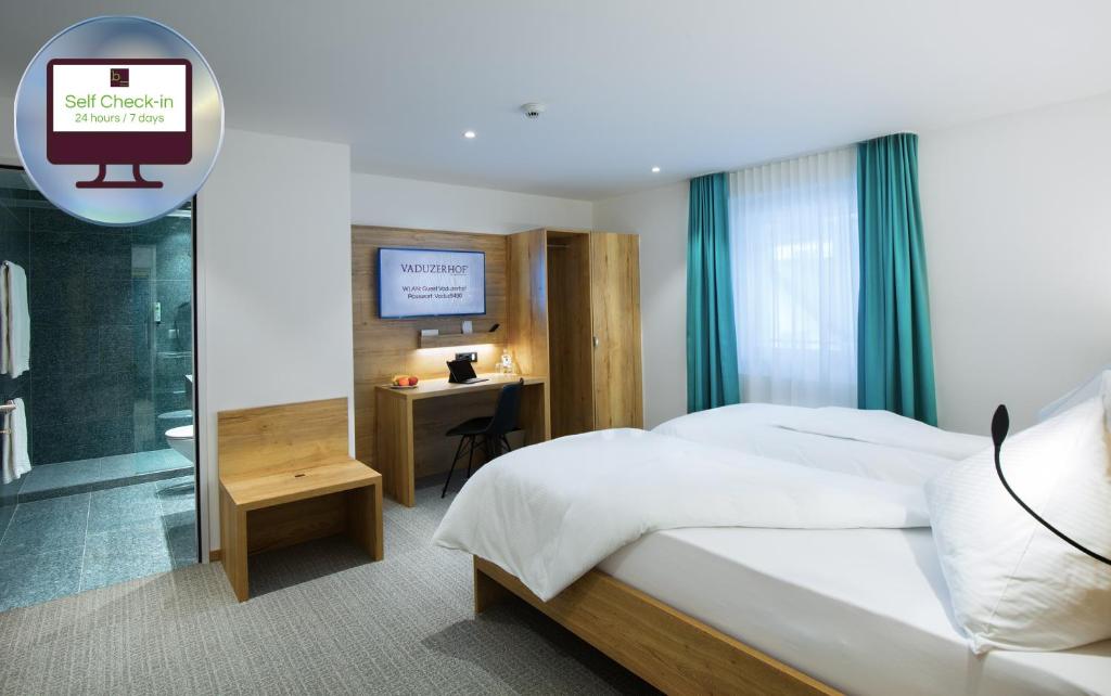 瓦杜兹Hotel Vaduzerhof by b-smart的一间卧室配有一张床、一张书桌和一台电视