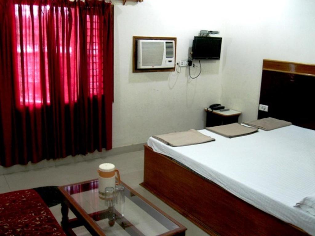 阿格拉阿贾伊国际酒店的一间卧室配有床、红色窗帘和桌子