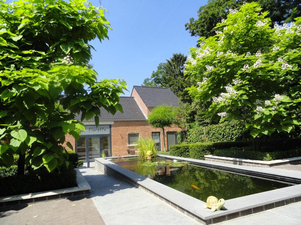 OverpeltB&B De Floreffe的一座花园,在一座建筑前设有一个池塘