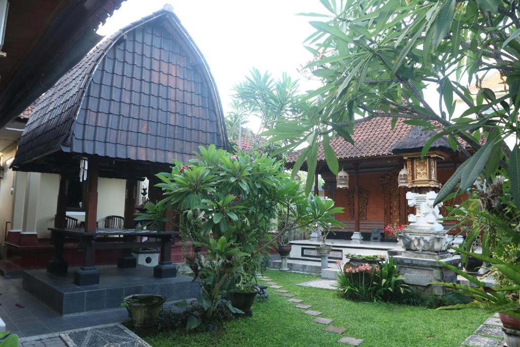 沙努尔Sekar Waru Homestay的一座房子,拥有种有树木的庭院和喷泉