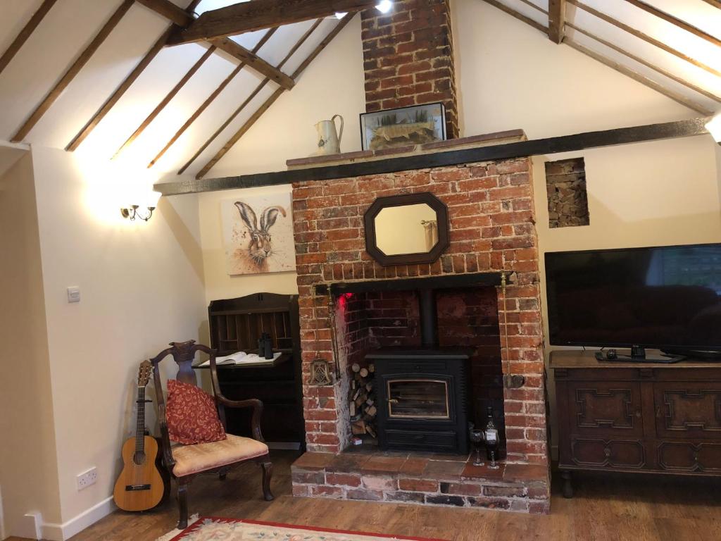 奥尔德堡Marsh View Cottage, Aldeburgh的一间带砖砌壁炉和电视的客厅